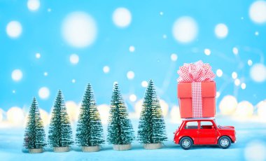 Çatıda Noel hediyeleri olan kırmızı oyuncak araba, arka planda çelenk, sığ alan derinliği.