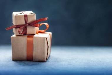 Koyu arkaplanda kahverengi kurdeleli hediye kutuları ve hediye paketleri.