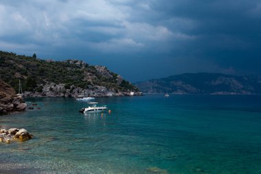 Arka planda dağ ve tekne olan bir su kütlesi.