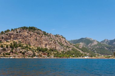Kahverengi bir dağın arka planındaki turist köyünün deniz manzarası