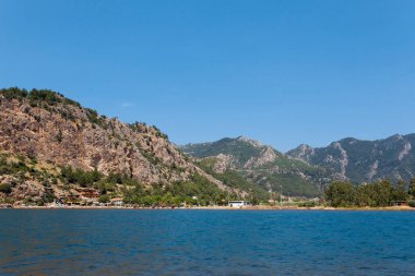 Kahverengi bir dağın arka planındaki turist köyünün deniz manzarası