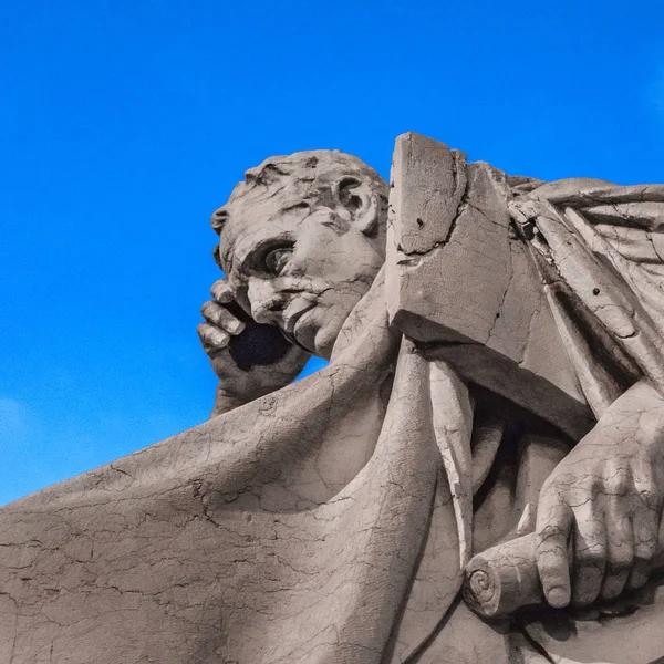 Low angle view thinker man statue against blue sky background