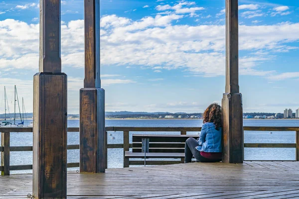 PUNTA DEL ESTE, URUGUAY, OCTOBER - 2018 - Woman watching the sea at waterfront boardwalk in punta del este city, Uruguay