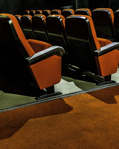 Interior dark scene at empty cinema with red chairs as main subject.