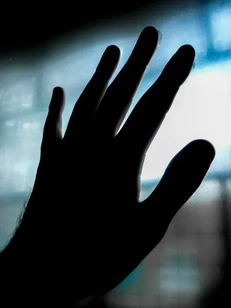 High contrast photo left hand touching blurred window glass