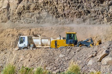 Kayalık arazide otoyol inşaatındaki kamyonlar, San Juan vilayeti, Arjantin