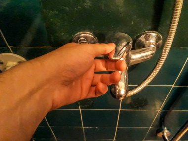 Yüksek açılı çekim el duş musluğuna dokunuyor.