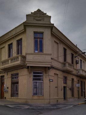 Bulutlu bir gökyüzü, Ciudad Vija, Montevideo City, Uruguay altında klasik mimarisi olan büyük, eski bir köşe binasının göz hizasında bir görüntüsü.