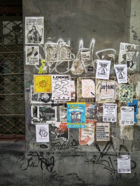 Montevideo, Uruguay: 8 Ağustos 2024: Eski, yırtık ve katmanlı kağıt posterleri ve çıkartmalarla kaplı yıpranmış beton bir duvarın dokulu arka planı. 