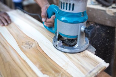 Erkek marangoz atölyesinde ahşap tahta üzerinde elektrikli araçlarla çalışma.