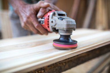 Erkek marangoz atölyesinde ahşap tahta üzerinde elektrikli araçlarla çalışma.