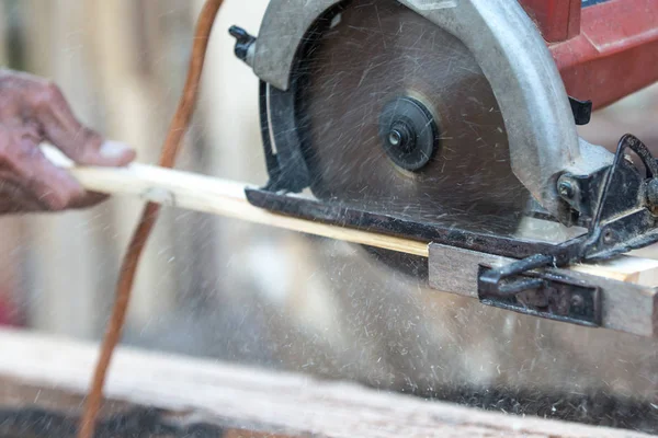 Male carpenter working with electric tools on wooden plank in workshop.