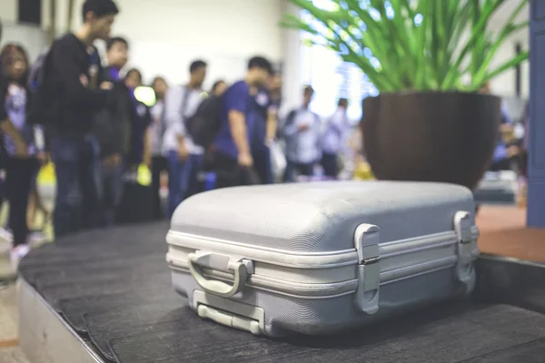 Wheeled suitcase on a luggage belt at the airport terminal.