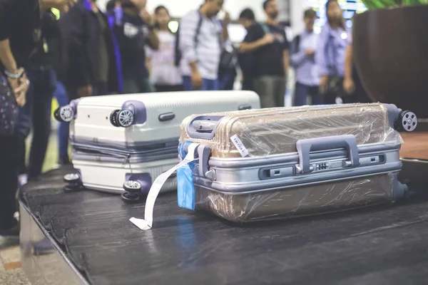 Wheeled suitcase on a luggage belt at the airport terminal.