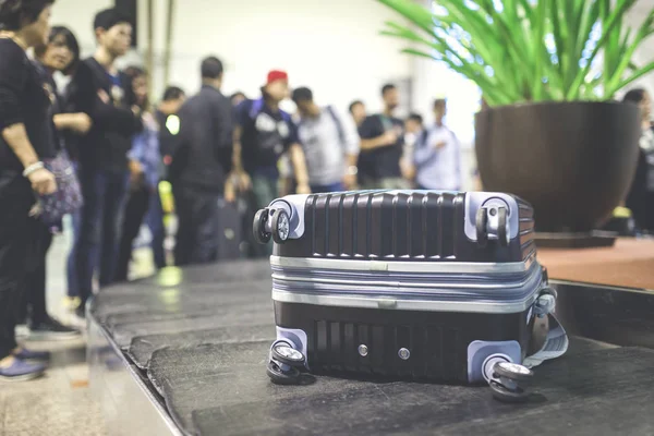 Wheeled suitcase on a luggage belt at the airport terminal.