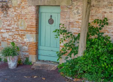 : Lavaur Midi Pyrenees, Fransa - 4 Ağustos 2017 eski yeşil kapı içinde bir tuğla duvar, Sonraki bazı bitkiler