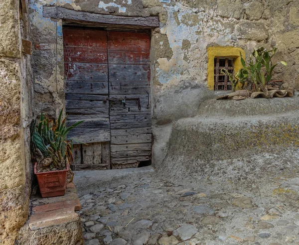 Calcata, Lazio, İtalya - 9 Eylül 2017: Küçük ve eski ahşap kapı bazı bitkilerde dar bir geçit ile