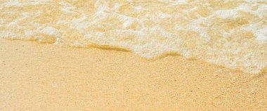 Sahilde kumdan arkaplan desenli berrak bir deniz dalgası 