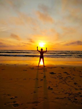 Güneş batımında sahilde onun elinde tutan genç