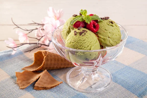 Green ice cream in a glass sprinkled with lasagne. And chocolate on a wooden table