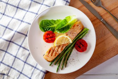 Kızarmış somon bifteği ve taze sebzeli domates..