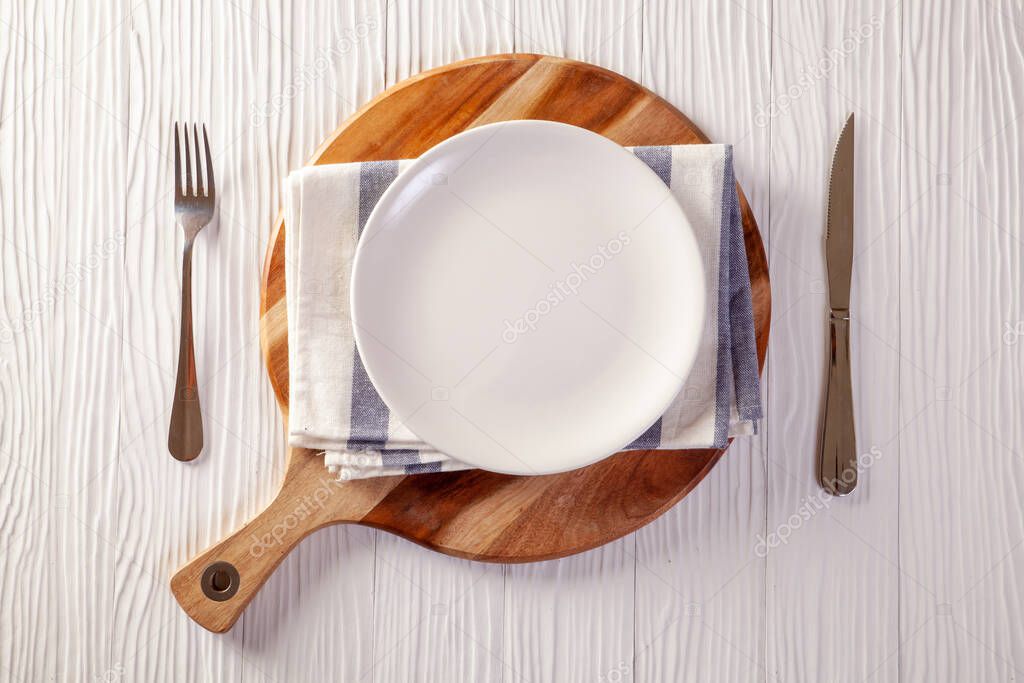 Empty plate on checkered tablecloth on white wooden table