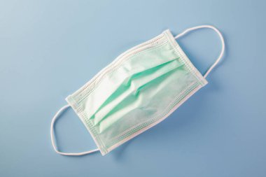 Plastik kulaklıklı bir maske. Ağız ve burnu örtmek için tipik 3 katlı cerrahi maske. Bakterilerin prosedür maskesi. Koruma kavramı.