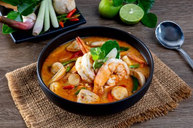 Tahta bir masada, siyah bir kasede karides Tom Yum