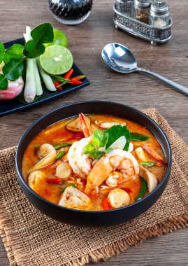 Tahta bir masada, siyah bir kasede karides Tom Yum