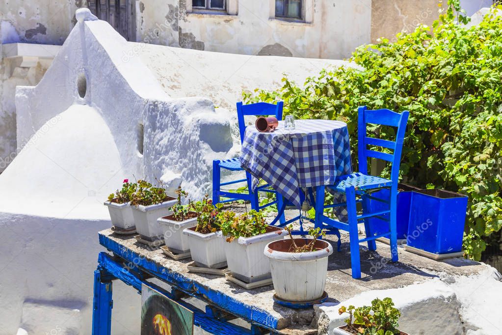 Traditional Greek street taverna with blue chairs . Naxos island