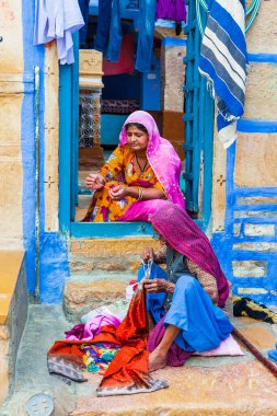  Geleneksel Hint ailesi. Elbise diken kadınlar. Jaisalmer caddesinde 2013 Şubatında çekim yapılmış. Rajasthan, Hindistan