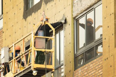 Sıkı şapkalı inşaat işçileri ön cephede çalışıyor.