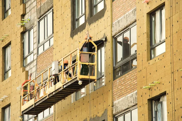 Trabalhadores da construção em chapéus duros trabalham na fachada — Fotografia de Stock