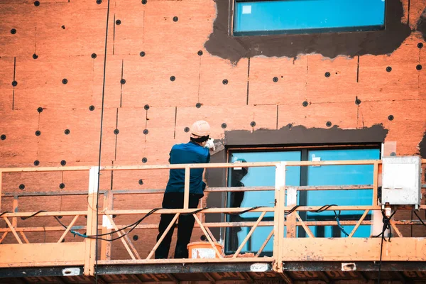 Trabajadores de la construcción con sombreros duros trabajan en la fachada — Foto de Stock