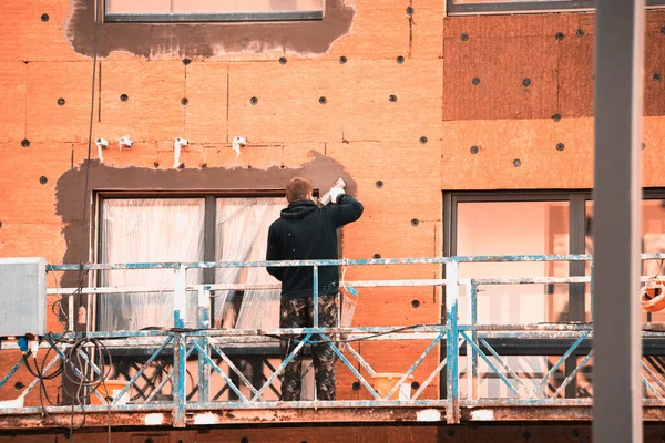 Trabajadores de la construcción con sombreros duros trabajan en la fachada — Foto de Stock