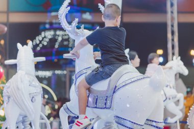 Çok güzel Asyalı küçük çocuk çocuk üstünde yuvarlak atlıkarınca Ren geyiği Noel lunapark, neşeli bir gitmek sürme.