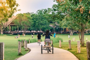 İnsanlar akşam genel parkta Bisiklete binme tarafından egzersiz.