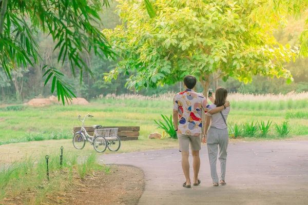 Back view of happiness Male and female couples walking hand in hand and fall in love along the public park in the evening