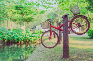 Eski kırmızı bisiklet Bahçe süslemeleri havuz kenarında bir çelik Ray üzerinde asılı.