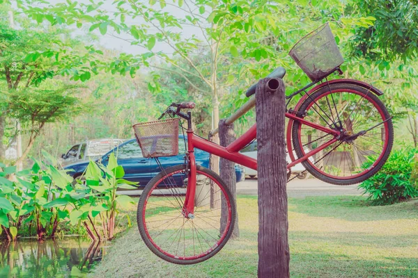 The old red bike hangs on a steel rail near the pool — Stock Photo, Image