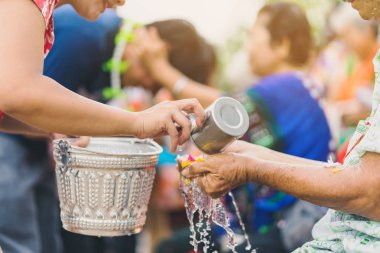 Thai people celebrate Songkran by pouring water and giving garlands to elder senior clipart