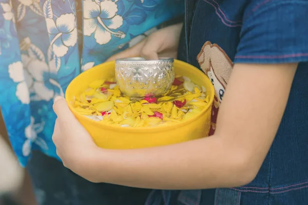 Люди тримають миску з водними парфумами з квіткою, яка готується до душу для ченців — стокове фото