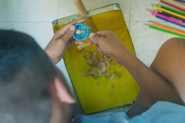 İlköğretim öğrencisi toz Pan içine renk kalemi keskinleştirmek 