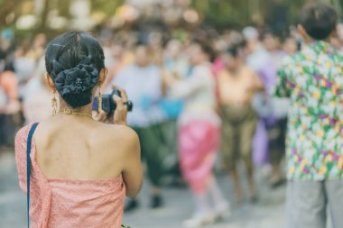 Back view of female in Thai dress  take a photo of a Thai dance parade in Songkran festival 
