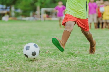 Asyalı erkek kamu futbol alanında gol topu tekme uygulama.