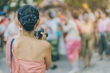 Back view of female in Thai dress  take a photo of a Thai dance parade in Songkran festival