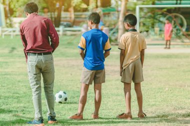 Asyalı erkek kamu futbol alanında gol topu tekme uygulama.