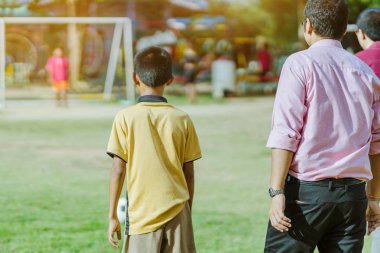 Asyalı erkek kamu futbol alanında gol topu tekme uygulama.