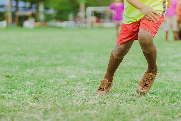 アジアの少年たちは、パブリックサッカー場でゴールを決めるためにボールを蹴る練習. — ストック写真