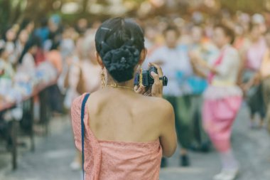 Back view of female in Thai dress  take a photo of a Thai dance parade in Songkran festival 